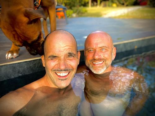 two men in a swimming pool with an elephant at Habitation Caféière Samana Beauséjour in Pointe-Noire