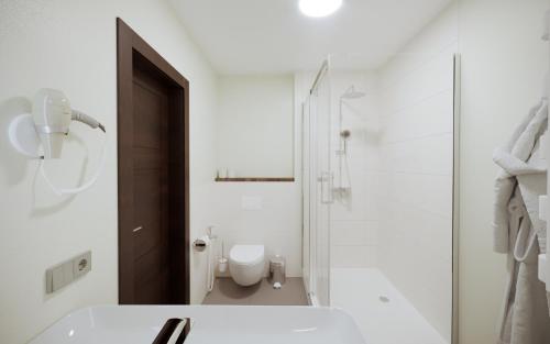 a white bathroom with a toilet and a sink at Drevny Grad Park-hotel in Lviv