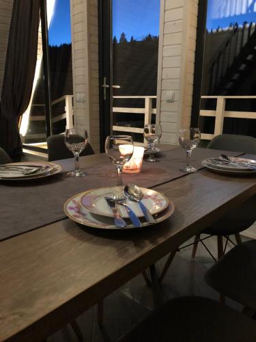 a wooden table with plates and wine glasses on it at Soul House in Pilipets