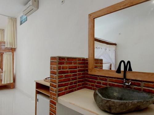 a bathroom with a stone sink and a mirror at Sama Sama Amed in Amed