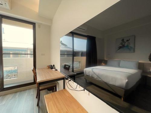 Schlafzimmer mit einem Bett, einem Schreibtisch und einem Fenster in der Unterkunft 戀戀館民宿 in Tainan