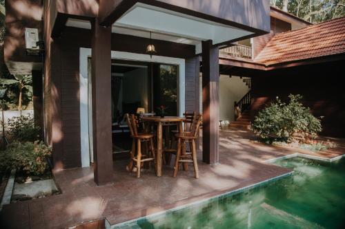 a patio with a table and chairs next to a pool at 101 Resort & Spa, Janda Baik in Kampong Sum Sum