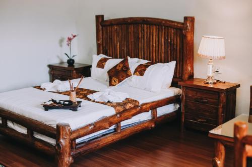 Un dormitorio con una gran cama de madera con sábanas blancas. en 101 Resort & Spa, Janda Baik, en Kampong Sum Sum