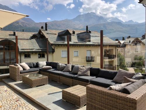 a patio with a couch and wicker furniture on a roof at Arsa Lodge Silvaplana in Silvaplana