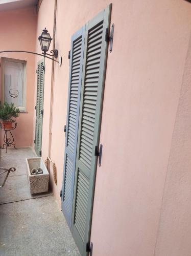 a door with blue shutters on a pink wall at Maison Platone Centre in Alessandria