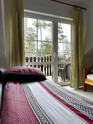a large bed in a bedroom with a large window at Dom pod Sosnami in Pobierowo