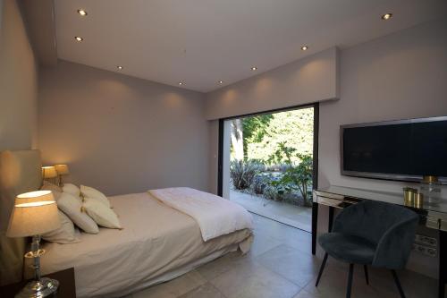 Schlafzimmer mit einem Bett und einem Flachbild-TV in der Unterkunft Serendipity in Vallauris