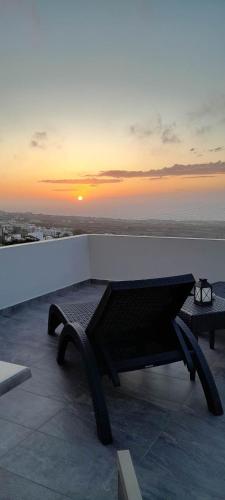 a bench sitting on top of a building with the sunset at Kiklamino Sunset Studios in Oia