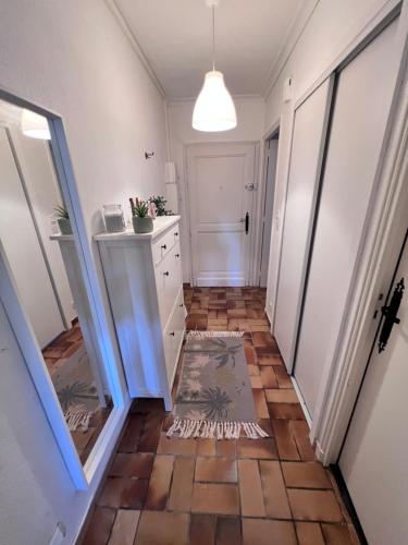 un couloir avec du carrelage et une armoire blanche dans l'établissement Sympathique studio en Rez de jardin dans résidence, à Hyères