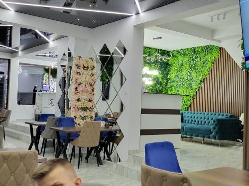 a restaurant with blue chairs and tables and a green wall at Вилно селище PARADISE VIEW in Sarnitsa