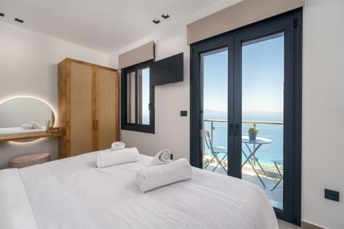 een slaapkamer met een wit bed en uitzicht op de oceaan bij Kalma Luxury Villas in Kalamata