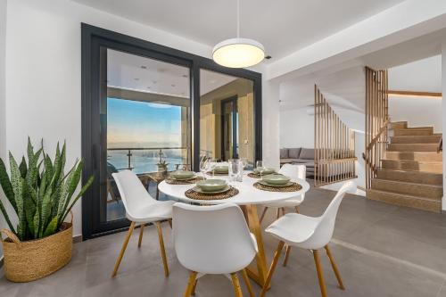 a dining room with a white table and white chairs at Kalma Luxury Villas in Kalamata