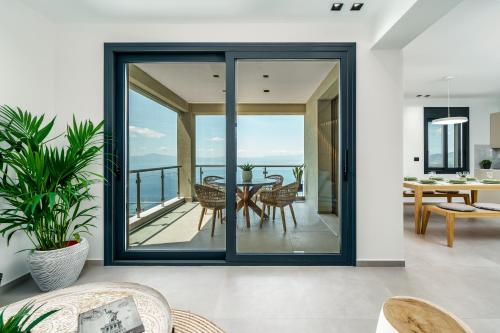 een open woonkamer met glazen schuifdeuren en een eettafel bij Kalma Luxury Villas in Kalamata