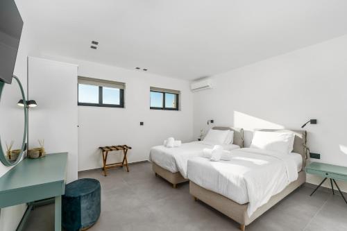 a white bedroom with two beds and a desk at Kalma Luxury Villas in Kalamata