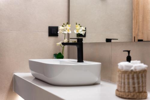 a bathroom sink with a faucet and flowers on a counter at Kalma Luxury Villas in Kalamata