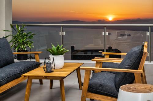 a balcony with two chairs and a table with a sunset at Kalma Luxury Villas in Kalamata