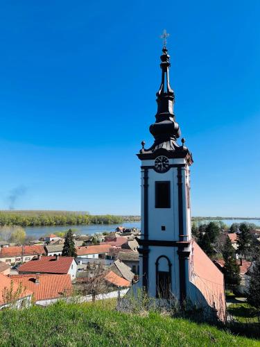 a clock tower on top of a building with a town at Fruškogorska kuća - Andrevlje lounge, naselje Testera in Čerević