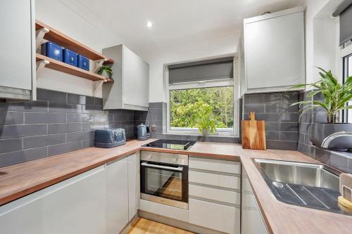 a kitchen with white cabinets and a sink and a window at Stylish Maisonette near the heath with Free parking & Wi-Fi in Kent
