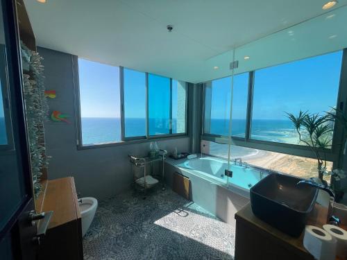 uma casa de banho com banheira e uma grande janela em Carmel Holiday Apartments em Netanya