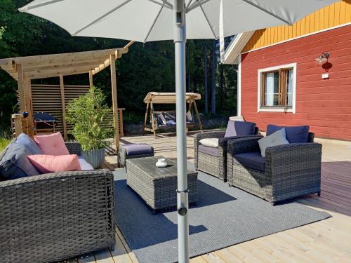 a patio with wicker chairs and an umbrella at VillaTorppa in Jämsä