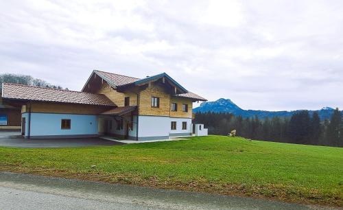 a house on a grassy hill with mountains in the background at Landhaus Stadlmann in Thalgau