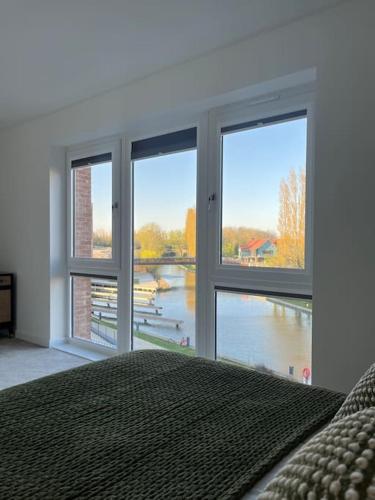 a bedroom with large windows with a view of a river at Outstanding 4-Bedroom Town House By Valore Property Services in Milton Keynes