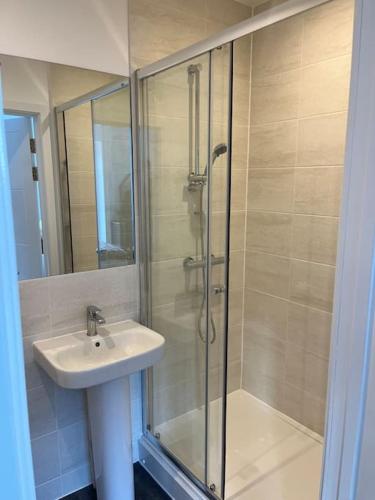 La salle de bains est pourvue d'un lavabo et d'une douche avec une porte en verre. dans l'établissement Outstanding 4-Bedroom Town House By Valore Property Services, à Milton Keynes