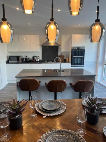a kitchen with a wooden table with chairs and a counter at Outstanding 4-Bedroom Town House By Valore Property Services in Milton Keynes