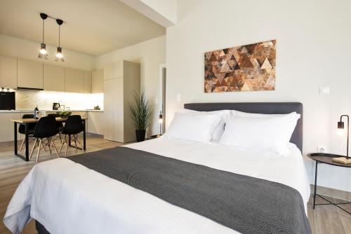 a bedroom with a large white bed and a kitchen at Aellō luxury apartments in Markopoulo