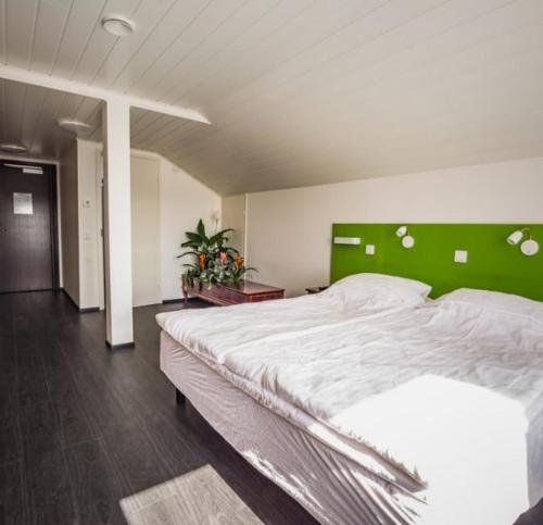 a bedroom with a large bed with a green headboard at Bed and Breakfast Artjärvi in Artjärvi