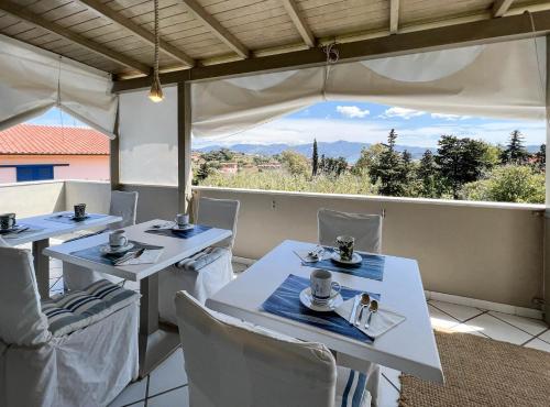 ポルトフェッラーイオにあるA casa di Enrico B&Bの景色を望むレストラン(白いテーブルと椅子付)
