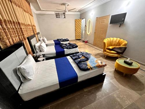 a hotel room with two beds and a chair at Shelton Royal Hotel in Multan