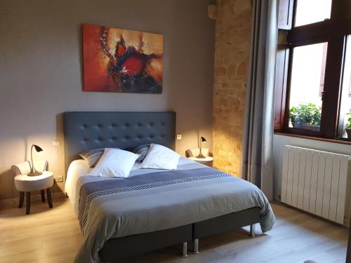 a bedroom with a bed and a painting on the wall at PETITS ANGES in Sarlat-la-Canéda