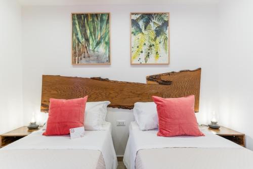 two beds in a room with red and white pillows at Mama Tita Rooms and Breakfast in Palermo