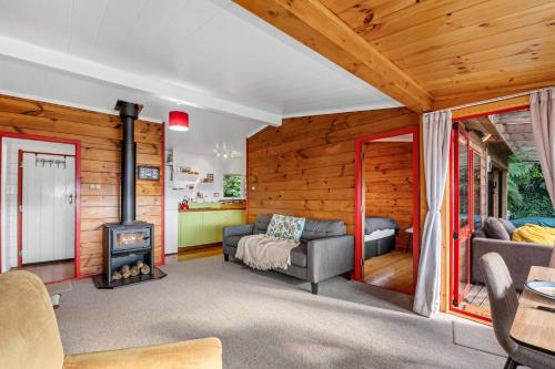 a living room with a fireplace in a wooden house at Lakeside Lookout - Lake Tarawera Holiday Home in Lake Tarawera