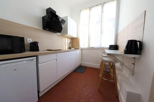 a kitchen with white cabinets and a tv on the wall at Studio boulevard Schloesing in Marseille