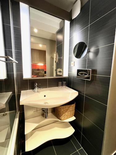 une salle de bain avec un lavabo et un miroir dans l'établissement Maïa, Joli appt proche gare de Caen, à Caen