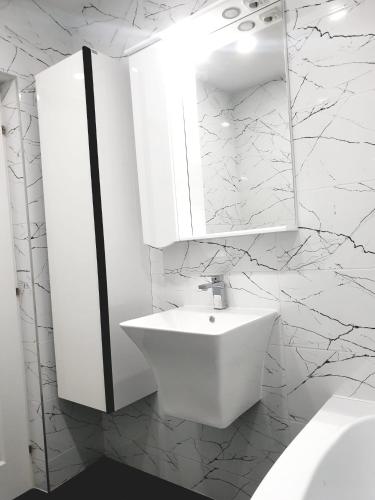 a white bathroom with a sink and a mirror at Garsoniera in Dorohoi
