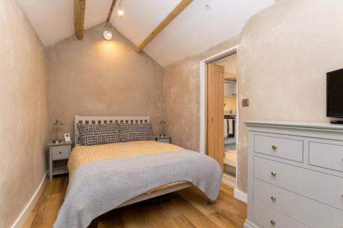 um quarto com uma cama, uma cómoda e uma televisão em Ferrymans Cottage - Historic Listed Building em Menai Bridge