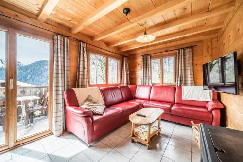 a living room with a red couch and a large window at Chalet Nid Zut in Châtel