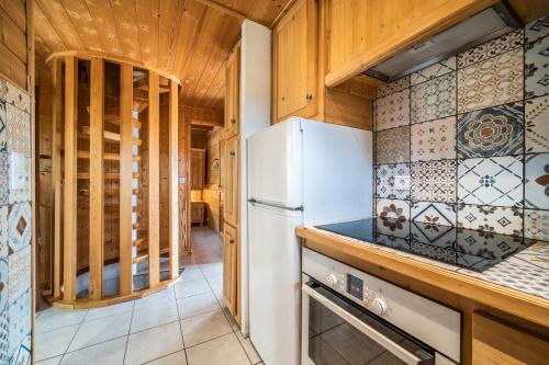 a kitchen with a white refrigerator and wooden cabinets at Chalet Nid Zut in Châtel