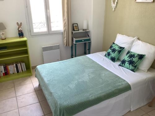 a bedroom with a bed with a green blanket and pillows at Les Oliviers in Mallemort