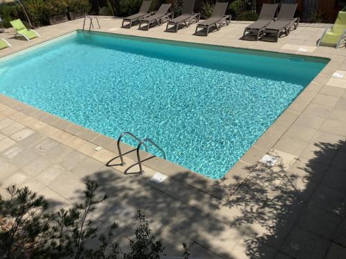 une grande piscine avec des chaises dans l'établissement Les Oliviers, à Mallemort