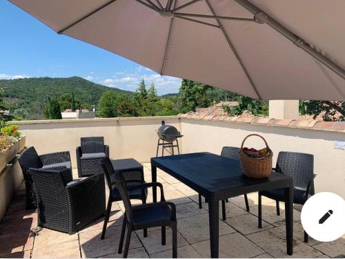 a patio with a table and chairs and an umbrella at VillaSarda Drome in Sauzet
