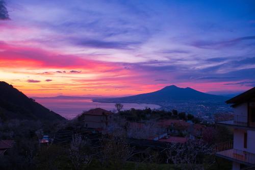 a sunset with a view of a city and a mountain at Villa Somma Apartments in Pimonte