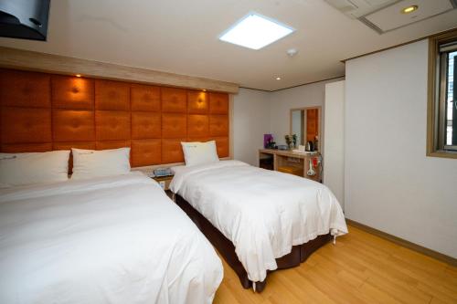 2 letti in una camera con lenzuola bianche di Daeyoung Hotel Myeongdong a Seul
