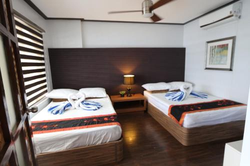 a bedroom with two beds and a table with a lamp at Noni's Resort in Alitagtag