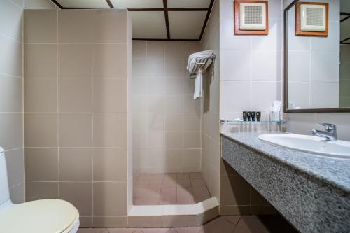 uma casa de banho com um chuveiro, um lavatório e um WC. em Botany Beach Resort em Na Jomtien