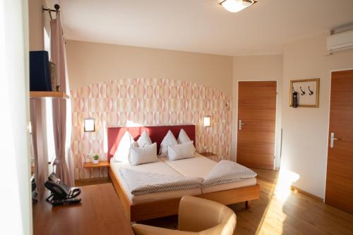 a bedroom with a bed with a red headboard at Restaurant Hotel Schrott in Kaibing