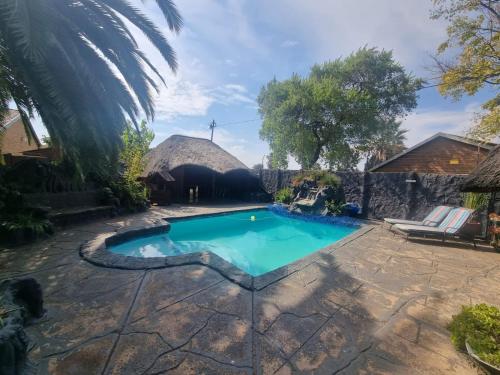 a swimming pool in a yard with a thatched building at Luxury Secured Apartment in Centurion